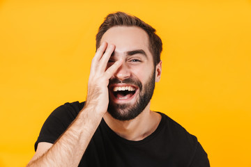 Image of brunette man in black t-shirt laughing and touching his face