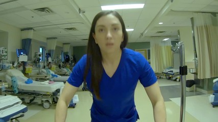Point of view of a patient looking up from a gurney as a nurse pushes it through a hospital ward and down a hallway.