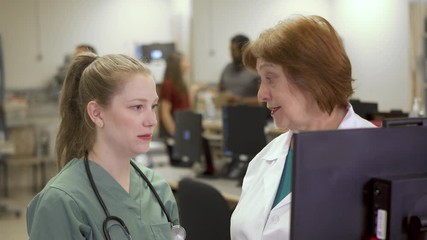 An experienced doctor tries to encourage a young nurse who looks like she is about to cry after a hard day.