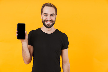 Image of attractive man wearing t-shirt smiling and holding cellphone