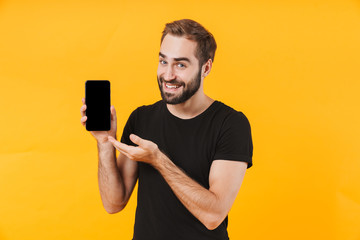 Image of handsome man wearing t-shirt smiling and holding cellphone