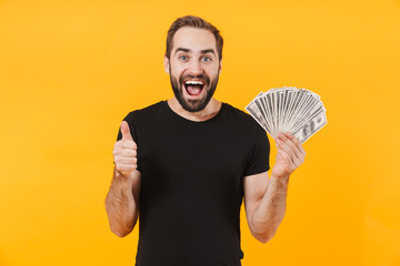 Image of happy man wearing t-shirt smiling and holding money cash