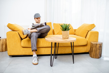 Handyman in workwear sitting on the yellow couch while resting after the work