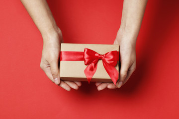 Woman holds a gift on a red background. Top view.