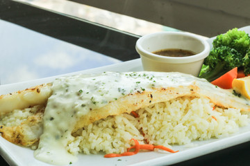 Grilled Pangasius Fillet with rice and topping with tartar sauce on white plate served with Vegetables