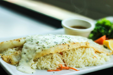 Grilled Pangasius Fillet with rice and topping with tartar sauce on white plate served with Vegetables