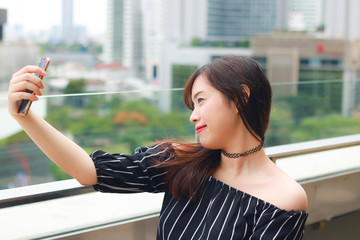 Asian beautiful girl taking a selfie on rooftop's department store in Bangkok, Thailand