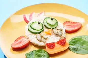 close up view of plate with fancy face made of food for childrens breakfast on blue background