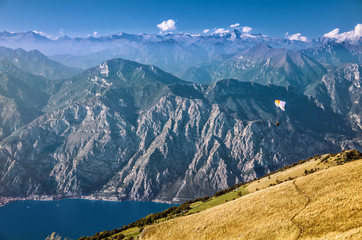 View on Alps and a paraglider over Garda lake from the mountain Monte Baldo, Lombardy, Italy.