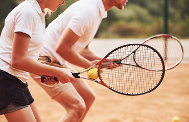 Side view. Coach teaching female student tennis game in the court outdoors