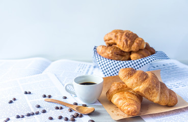 Close Up of Fresh Baked Croissant on wood table with Coffee Mug and  news paper on Relaxing Morning at Home, Bread and coffee, breakfast Healthy food of the city life