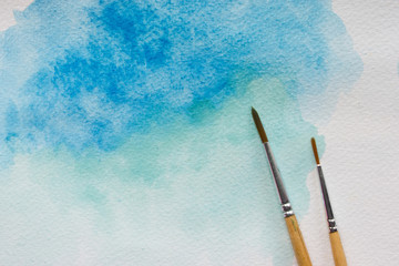 Paintbrushes on isolated watercolor painted background.