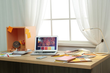 Designer's workplace with modern laptop and color palettes