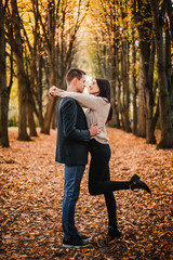 Beautiful young couple hugging in autumn park.