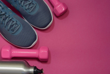 Sport sneakers and dumbbells on pink background with copy space for text. Sport objects background. Sports concept