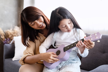 Mother teaching ukulele with beautiful daughter ,at studio music room,family activity,with happy feeling