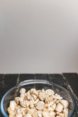 Cut forest champignons in glass bowl on black boards. Mushrooms on dark background.