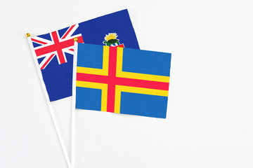 Fototapeta premium Aland Islands and Cayman Islands stick flags on white background. High quality fabric, miniature national flag. Peaceful global concept.White floor for copy space.