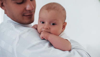 Stands and holds baby on the hands. Young pediatrician is in the clinic at daytime