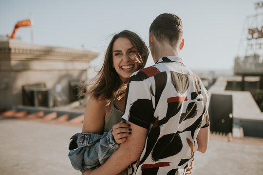 Young urban couple embracing each other on sunny rooftop