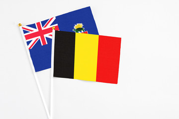 Belgium and Cayman Islands stick flags on white background. High quality fabric, miniature national flag. Peaceful global concept.White floor for copy space.