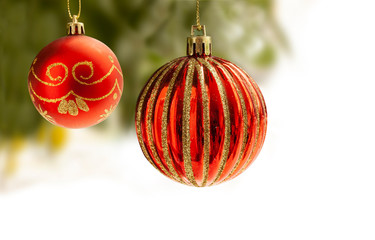 Red Christmas balls with gold decoration hanging from a Christmas tree with blurry background. Ball are partly isolated on white for copy writing on the blank space