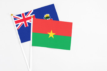 Burkina Faso and Cayman Islands stick flags on white background. High quality fabric, miniature national flag. Peaceful global concept.White floor for copy space.