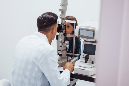 Young ophthalmologist is with little female visitor in the clinic