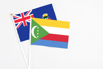 Comoros and Cayman Islands stick flags on white background. High quality fabric, miniature national flag. Peaceful global concept.White floor for copy space.