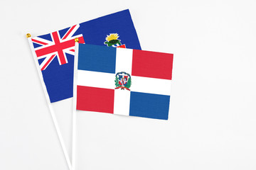 Dominican Republic and Cayman Islands stick flags on white background. High quality fabric, miniature national flag. Peaceful global concept.White floor for copy space.
