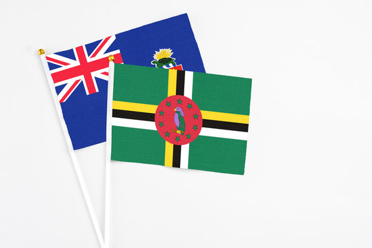 Dominica and Cayman Islands stick flags on white background. High quality fabric, miniature national flag. Peaceful global concept.White floor for copy space.
