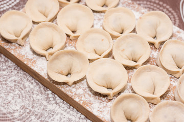 Dumplings - a dish of Russian cuisine on a wooden background. Cooking.