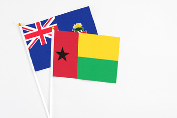 Guinea Bissau and Cayman Islands stick flags on white background. High quality fabric, miniature national flag. Peaceful global concept.White floor for copy space.
