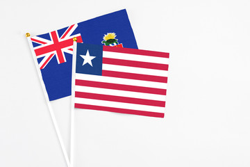 Obraz premium Liberia and Cayman Islands stick flags on white background. High quality fabric, miniature national flag. Peaceful global concept.White floor for copy space.