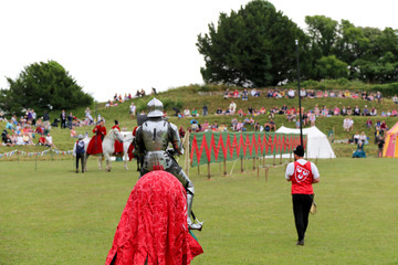 Knight in armour on a horse at a joust with crowds