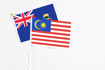 Malaysia and Cayman Islands stick flags on white background. High quality fabric, miniature national flag. Peaceful global concept.White floor for copy space.