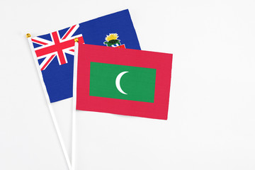 Maldives and Cayman Islands stick flags on white background. High quality fabric, miniature national flag. Peaceful global concept.White floor for copy space.