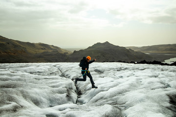 Guy jumping over small stream on Solheimajokull glacier