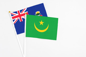 Mauritania and Cayman Islands stick flags on white background. High quality fabric, miniature national flag. Peaceful global concept.White floor for copy space.