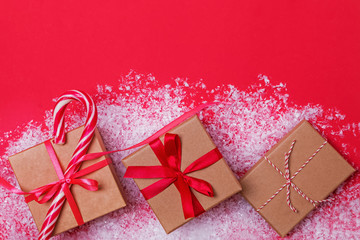 Christmas presents in boxes on red table with snow.