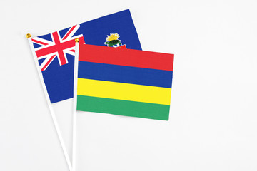 Mauritius and Cayman Islands stick flags on white background. High quality fabric, miniature national flag. Peaceful global concept.White floor for copy space.