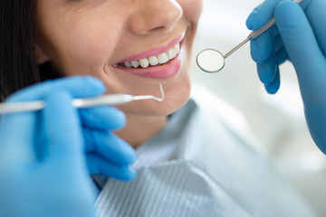 dentist examining teeth of young happy woman, close-up shot