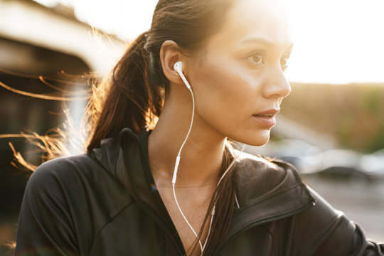 Image closeup of young sporty woman using earphones while working out