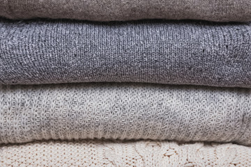 Bunch of knitted warm sweaters, different knitting patterns folded in stack