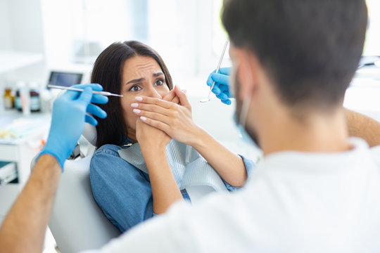 Female patient is afraid of dentist in modern dental clinic