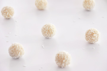 White chocolate candies with coconut filling on a white background. High key photo.