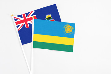 Rwanda and Cayman Islands stick flags on white background. High quality fabric, miniature national flag. Peaceful global concept.White floor for copy space.