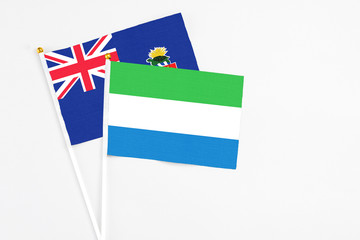 Sierra Leone and Cayman Islands stick flags on white background. High quality fabric, miniature national flag. Peaceful global concept.White floor for copy space.