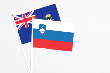 Slovenia and Cayman Islands stick flags on white background. High quality fabric, miniature national flag. Peaceful global concept.White floor for copy space.