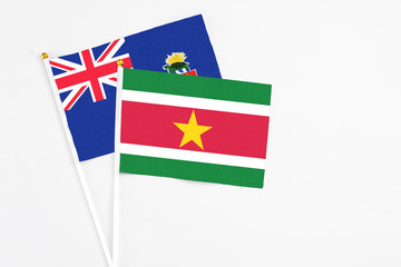 Suriname and Cayman Islands stick flags on white background. High quality fabric, miniature national flag. Peaceful global concept.White floor for copy space.